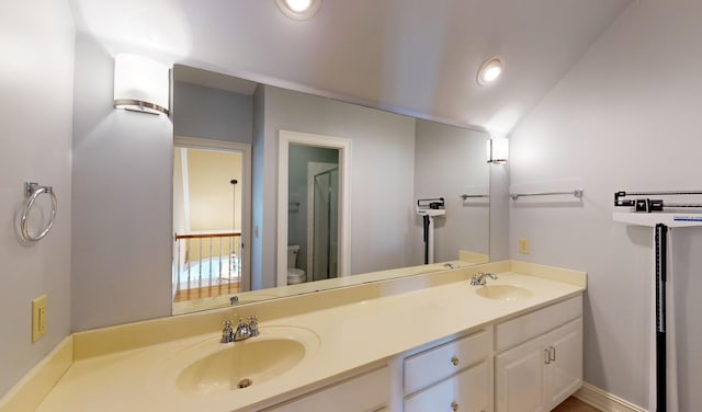 bathroom with vanity, toilet, and lofted ceiling