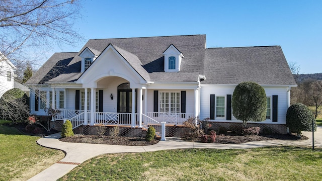 new england style home featuring a porch and a front yard