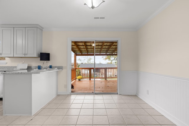 kitchen featuring light stone countertops, light tile patterned floors, and crown molding