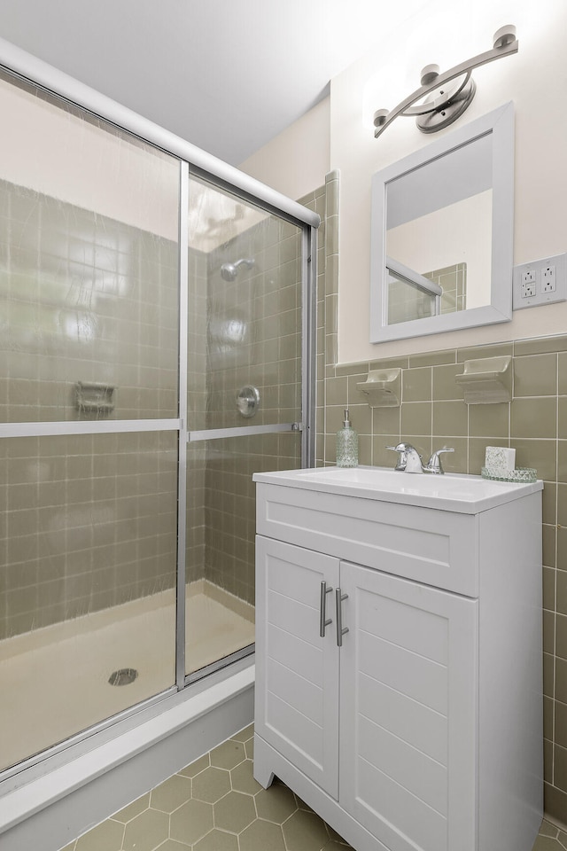 bathroom featuring tile patterned floors, vanity, tile walls, and walk in shower