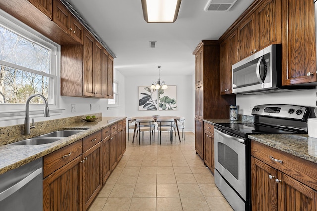 kitchen featuring an inviting chandelier, light tile patterned floors, appliances with stainless steel finishes, pendant lighting, and sink