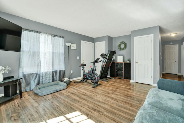 exercise area featuring wine cooler, wood finished floors, and baseboards