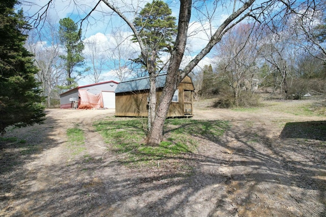 view of yard featuring a shed, dirt driveway, a detached garage, and an outdoor structure