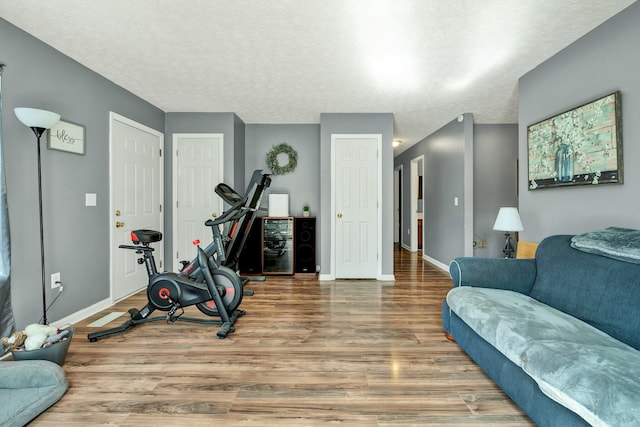 workout room featuring a textured ceiling, baseboards, and wood finished floors