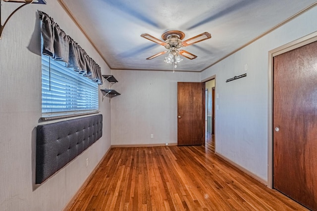 empty room featuring baseboards, ceiling fan, ornamental molding, and wood finished floors