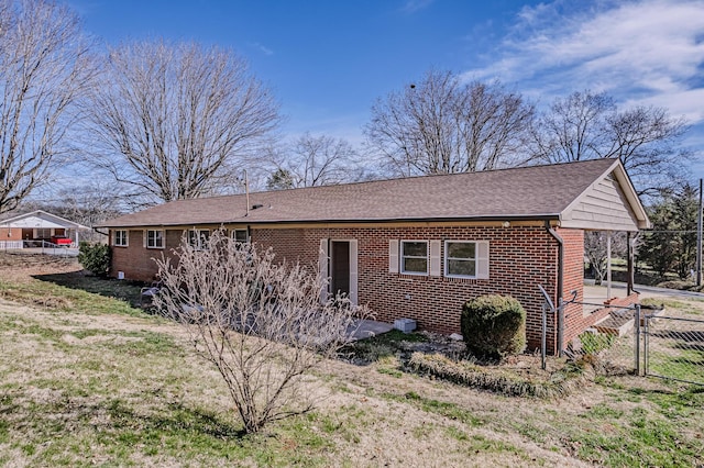 ranch-style house featuring brick siding, roof with shingles, fence, and a gate