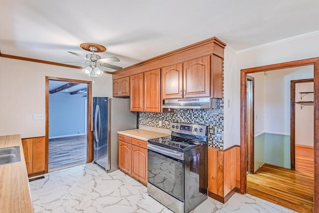 kitchen with marble finish floor, crown molding, light countertops, appliances with stainless steel finishes, and under cabinet range hood