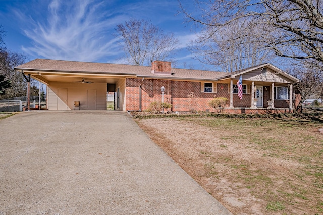 ranch-style house featuring brick siding, fence, driveway, a carport, and a chimney