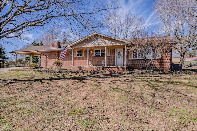 single story home featuring a chimney, covered porch, a front lawn, a carport, and brick siding