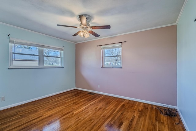 empty room featuring crown molding, baseboards, and wood finished floors