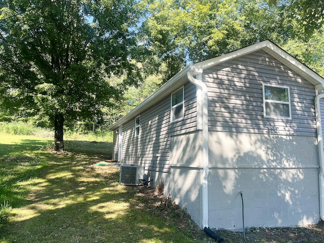 view of side of home with a yard and central AC