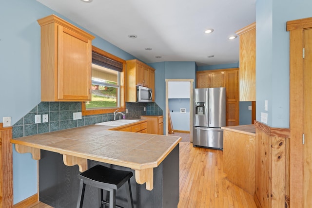 7105 Toestring Valley Rd, Spring City, TN 37381 - kitchen with appliances with stainless steel finishes, a peninsula, a sink, light wood-style floors, and backsplash