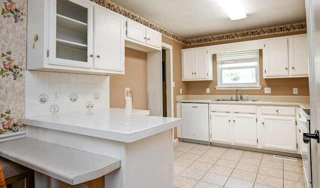 kitchen featuring dishwasher, sink, white cabinets, a kitchen breakfast bar, and kitchen peninsula