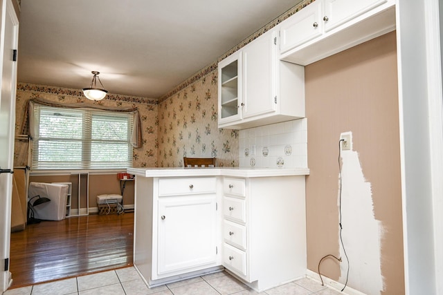 kitchen with decorative light fixtures, light tile patterned floors, kitchen peninsula, decorative backsplash, and white cabinets