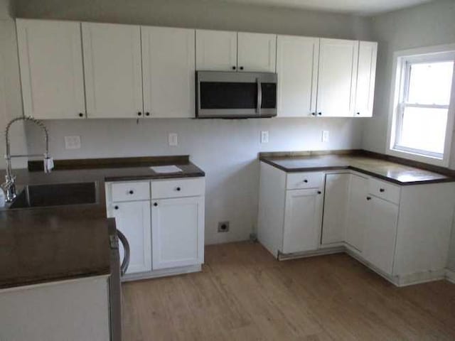 kitchen featuring light wood-type flooring, white cabinetry, and sink