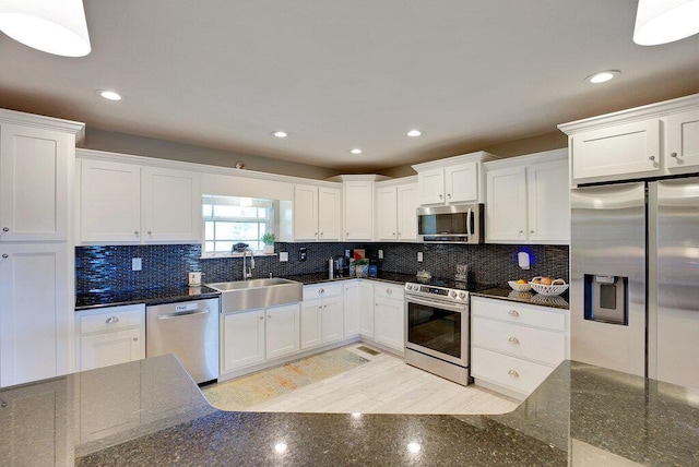 kitchen with tasteful backsplash, sink, stainless steel appliances, and white cabinetry