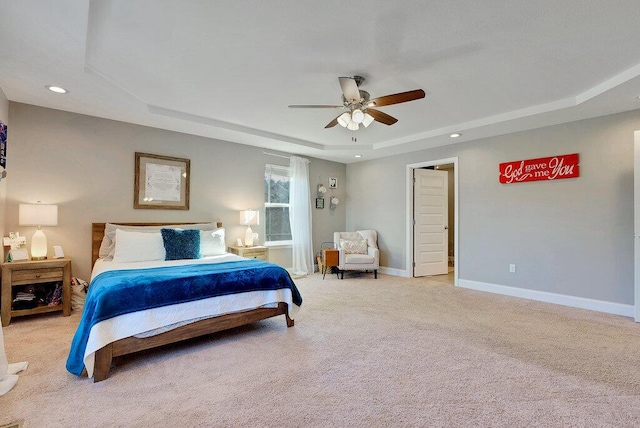 carpeted bedroom featuring ceiling fan and a tray ceiling