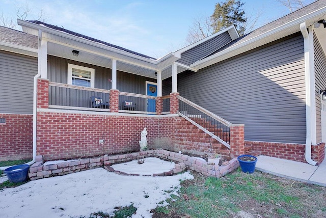 snow covered property entrance with covered porch