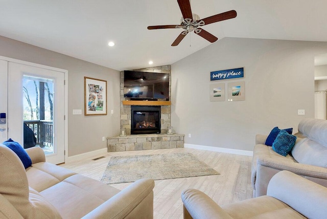 living room with ceiling fan, lofted ceiling, a fireplace, and light hardwood / wood-style flooring