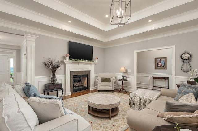 living room with a raised ceiling, hardwood / wood-style flooring, an inviting chandelier, and crown molding