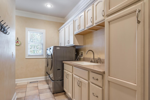 clothes washing area with cabinets, washer and clothes dryer, crown molding, sink, and light tile patterned floors