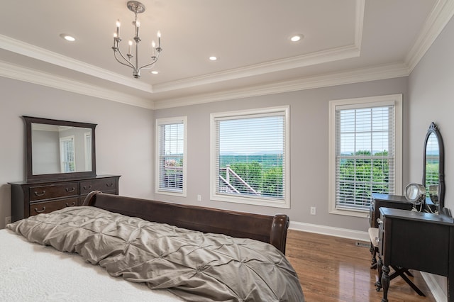 bedroom featuring a tray ceiling, an inviting chandelier, multiple windows, and hardwood / wood-style flooring