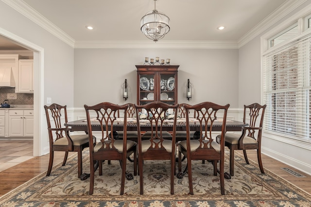 dining area featuring light wood-type flooring, ornamental molding, and an inviting chandelier