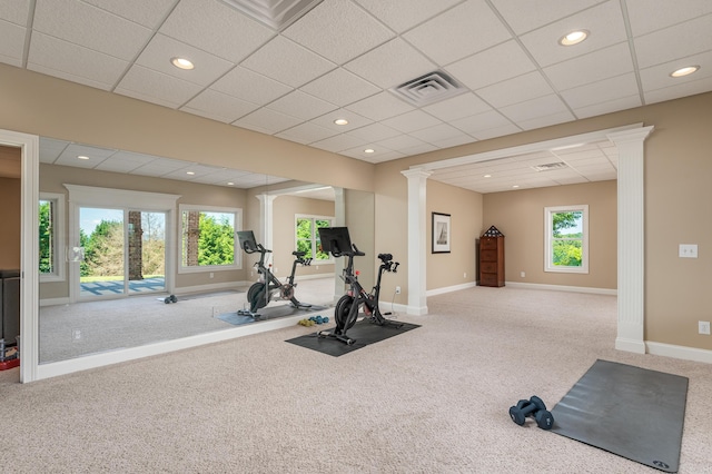 exercise room featuring carpet flooring, a paneled ceiling, and ornate columns