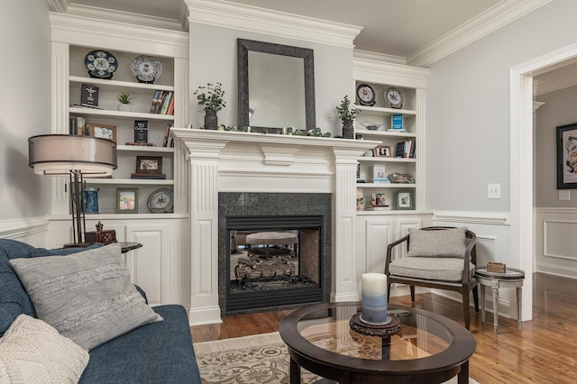 living area featuring wood-type flooring, built in features, and crown molding