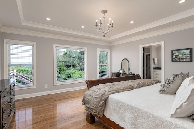 bedroom featuring wood-type flooring, crown molding, a tray ceiling, and ensuite bath