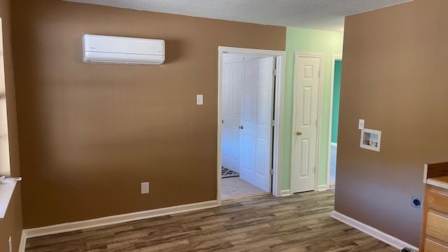 hall featuring a textured ceiling, hardwood / wood-style flooring, and a wall unit AC