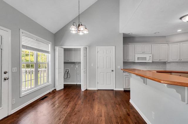 1031 Laurel Hill Dr, Dickson, TN 37055 - kitchen with white microwave, a chandelier, high vaulted ceiling, baseboards, and hanging light fixtures