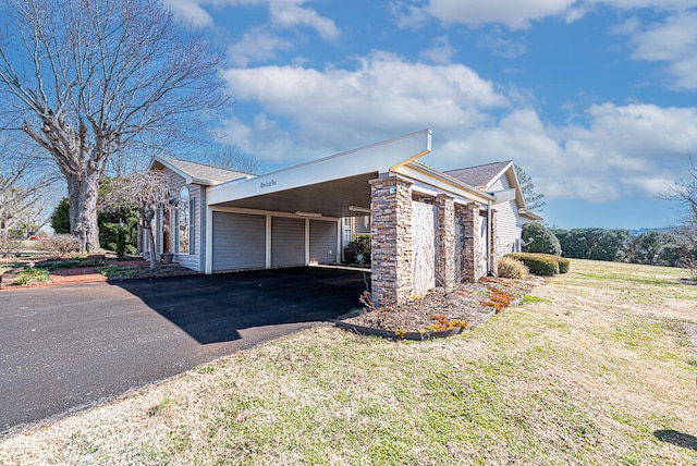 view of side of home with a carport, stone siding, a yard, and driveway