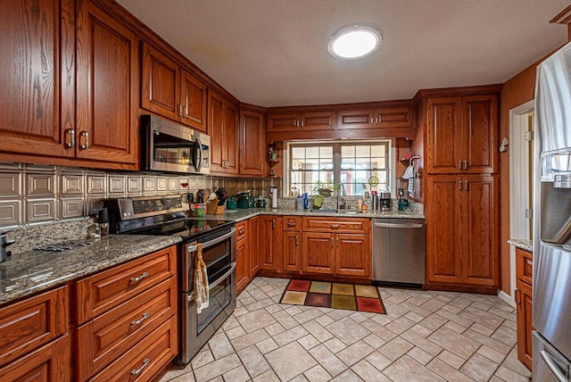 kitchen with stainless steel appliances, backsplash, a sink, and brown cabinets