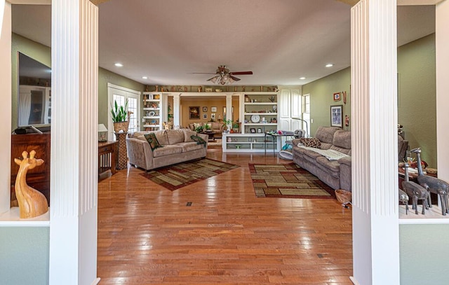 living area with decorative columns, built in features, hardwood / wood-style flooring, ceiling fan, and recessed lighting