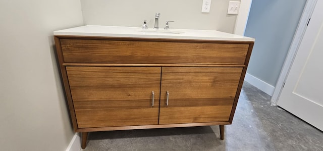 bathroom with baseboards, concrete flooring, and vanity