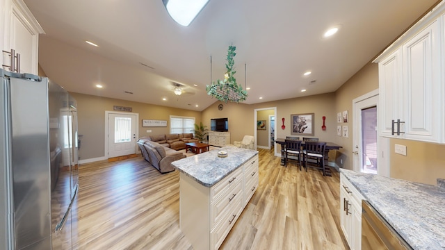 kitchen featuring appliances with stainless steel finishes, lofted ceiling, white cabinets, light stone countertops, and light wood-type flooring