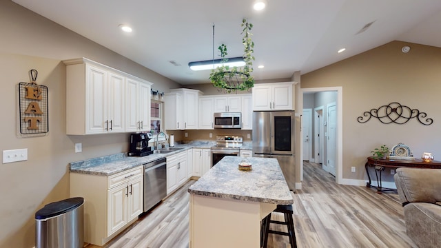 kitchen with sink, white cabinets, a center island, stainless steel appliances, and light wood-type flooring