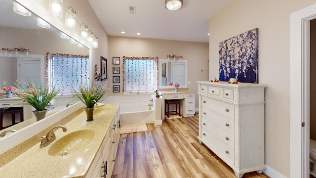 bathroom with vanity, toilet, hardwood / wood-style floors, and a tub