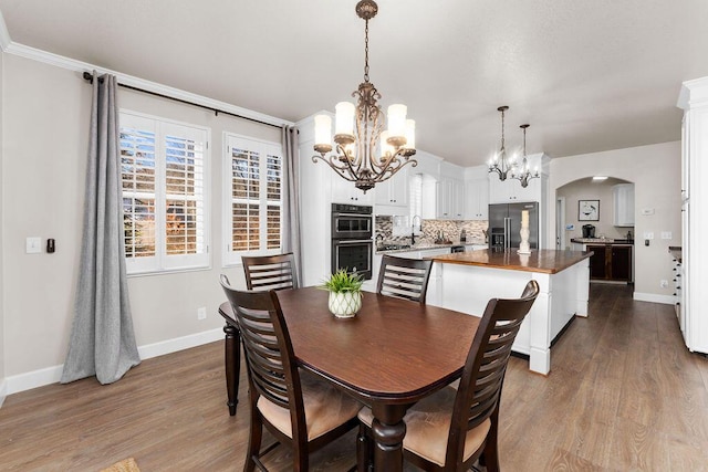 dining area with hardwood / wood-style flooring, sink, and an inviting chandelier