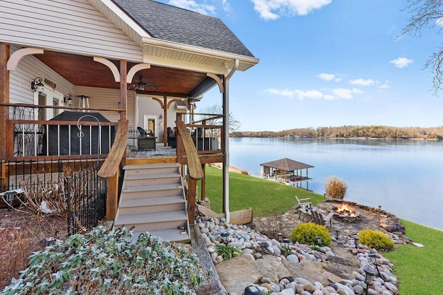 dock area featuring a fire pit, a lawn, and a water view