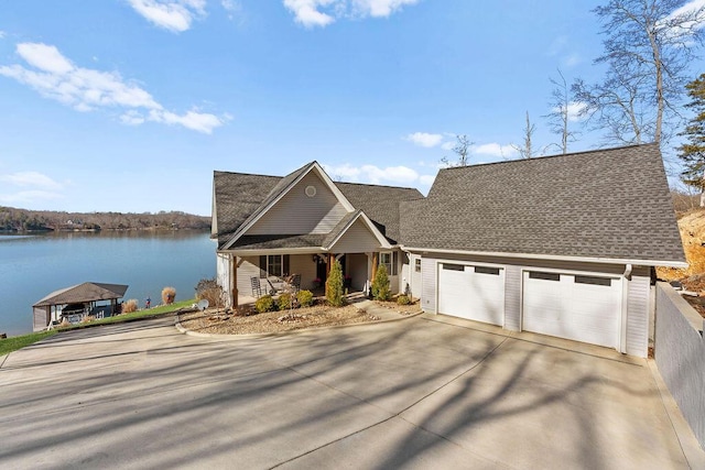 view of front of home with a garage, a porch, and a water view