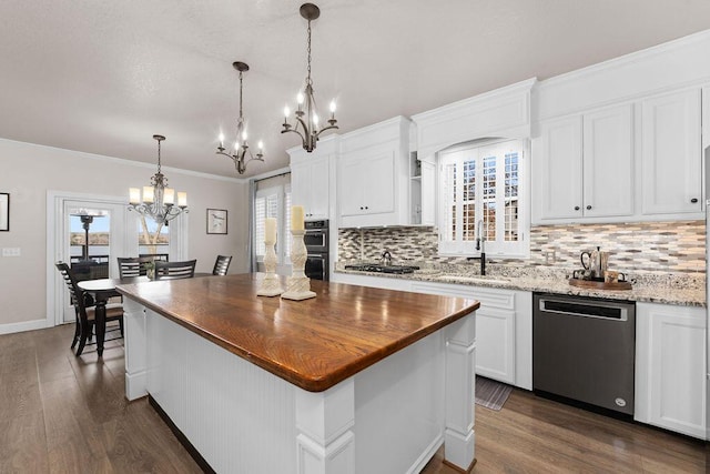 kitchen featuring pendant lighting, dishwasher, white cabinetry, light stone counters, and a kitchen island