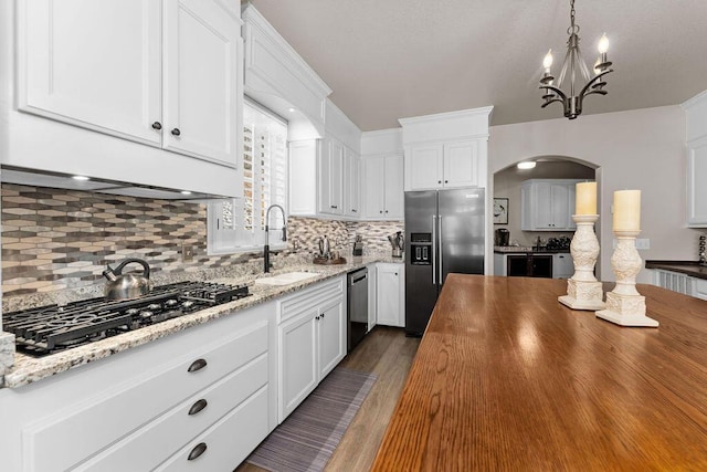 kitchen with sink, dark hardwood / wood-style flooring, pendant lighting, stainless steel appliances, and white cabinets