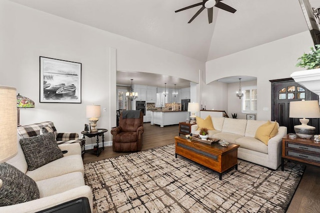 living room with ceiling fan with notable chandelier, high vaulted ceiling, and light hardwood / wood-style floors