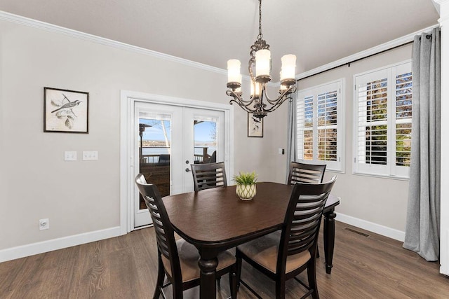 dining space featuring ornamental molding, dark wood-type flooring, an inviting chandelier, and french doors