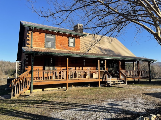 log cabin with metal roof, a chimney, a porch, and log exterior