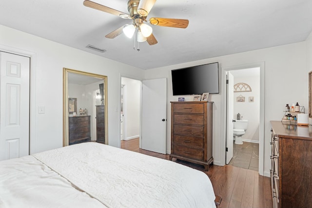 bedroom with a closet, ensuite bath, ceiling fan, and hardwood / wood-style floors