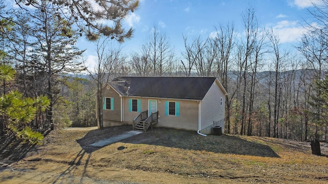 view of front of property featuring cooling unit and a view of trees