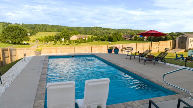 7083 Blue Springs Rd SE, Cleveland, TN 37311 - view of swimming pool featuring a storage unit, a patio area, a fenced backyard, and a wooded view